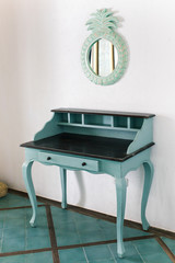Blue vintage table of drawers stands near white wall
