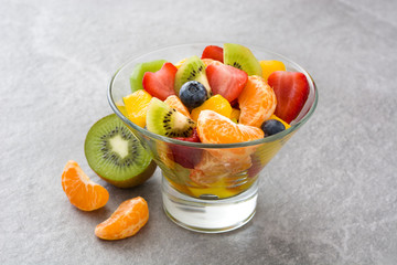 Fruit salad in crystal bowl on gray stone
