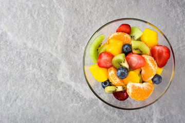 Fruit salad in crystal bowl on gray stone
