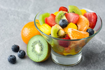Fruit salad in crystal bowl on gray stone
