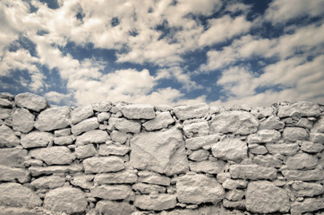 White stone wall under a blue sky with clouds