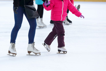 Naklejka premium the legs of an adult and child skating on the ice rink.