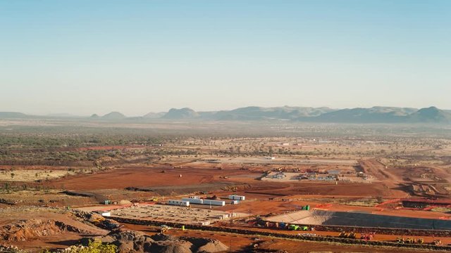 Static pan timelapse of a construction site on a mine while earthworks is in progress with heavy load machinery, trucks and tippers 
