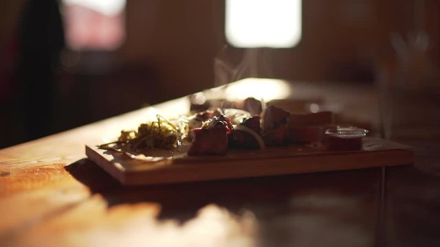 Close up footage of steaming fried meat lying on wooden tray on table in slowmotion