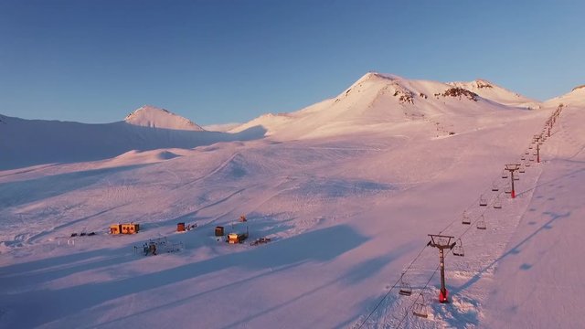 View from drone of mountain ski resort with poma lift during sunset in slowmotion