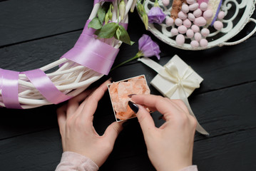 Girl unpack white gift box near flowers and cake on black wooden background