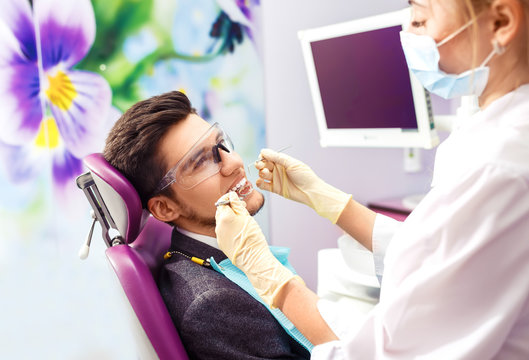 Portrait of male. smile face. Dental care Concept. Dental inspection is being given to Beautiful man surrounded by dentist and his assistant
