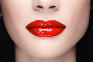Fototapeta premium Close-up shot of woman's lips with glossy red lipstick