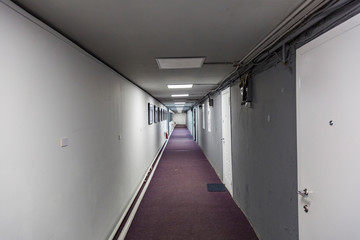 Long walkway between buildings with carpet and doors