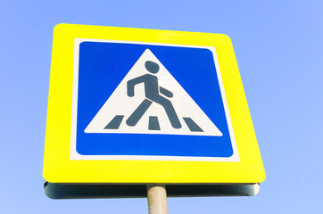 Road sign pedestrian crossing in background blue sky