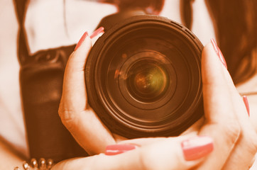 Fototapeta na wymiar SLR camera lens in girl female hand