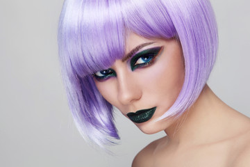 Young beautiful woman with fancy green make-up and violet wig