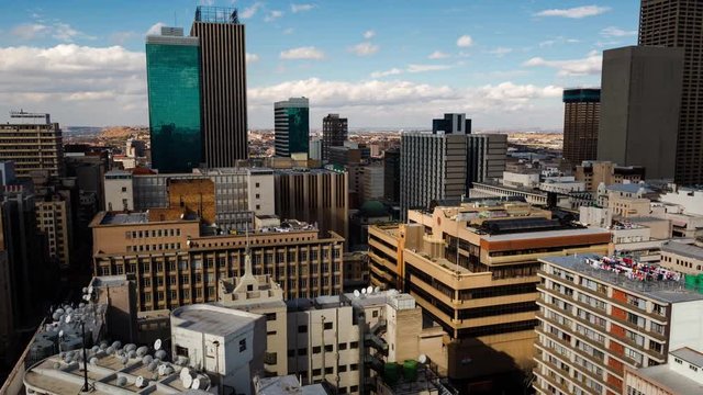 A slow panning timelapse across the city centre of Johannesburg (CBD) in the daytime with bright blue skies and cumulous clouds showing the High Court of South Africa, old Sun International and Carlton Tower