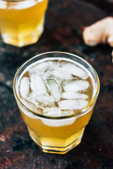 Ginger ale on black rustic surface with ice.