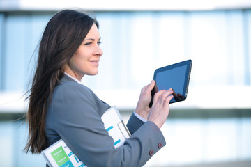 Businesswoman working on digital tablet outdoor over building background