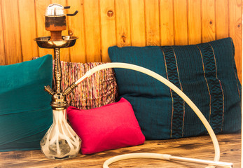 hookah among the colored cushions on the wood