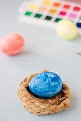 Deep blue easter egg on nest over bright background.