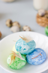 Green, yellow and blue easter eggs on ceramic bowl, bright and airy shot.