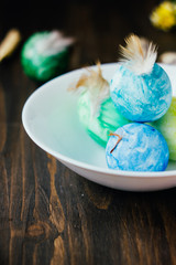 Blue, yellow and green color easter eggs on ceramic bowl over rustic table.