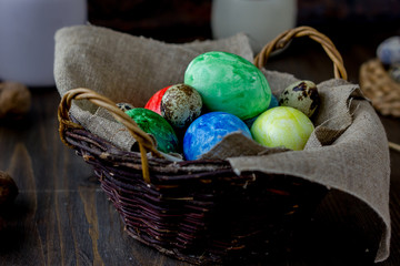 Colored easter eggs on basket over rustic table.