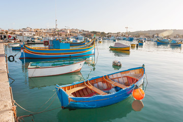 Obraz premium Mediterranean traditional colorful boats luzzu. Fisherman village in the south east of Malta. Early winter morning in Marsaxlokk, Malta.