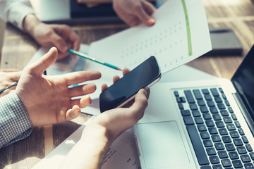 Group of business people working together. Loft office and smart casual dress code. Researching new product strategy. Laptop and paperwork on the table