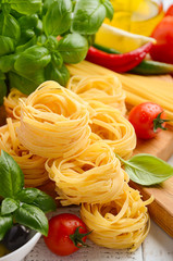 Pasta, vegetables, herbs and spices for Italian food on white wooden background, selective focus