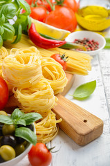 Pasta, vegetables, herbs and spices for Italian food on white wooden background, selective focus