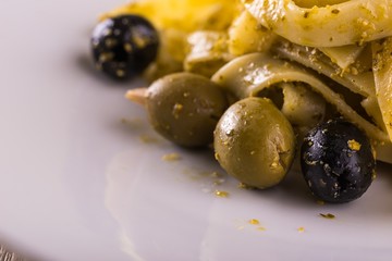 Detail of few olives with in portion of tagliatelle with green pesto