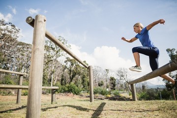 Woman jumping over the hurdles during obstacle course - Powered by Adobe