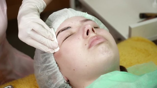 Beautician is making a microblading brocedure for a woman in beauty salon closeup