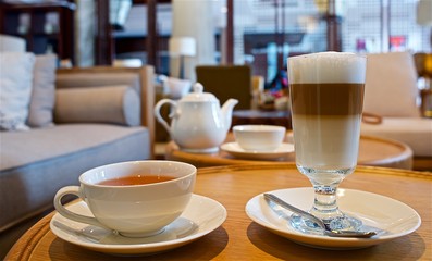Table with cup of bleack tea and glass of latte macchiato