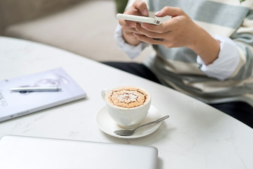 Asian businessman using mobile phone  during coffee break on table in coffee shop
