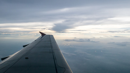 Fototapeta na wymiar The airplane wing on the beautiful cloudy and sky at early in the evening.