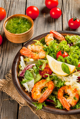 Seafood. Shellfish. Fresh lettuce salad with tomatoes, herbs and grilled fried shrimps prawns, on wooden rustic table, copy space 