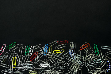 Paper clips isolated on black background. Office paper work concept background. Top view.