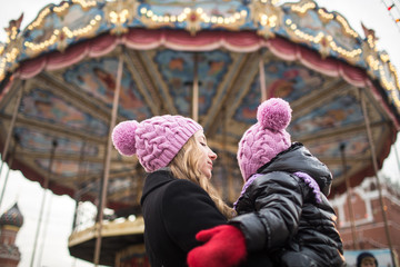 Mom and daughter at the Christmas market on the background of merry-go-round