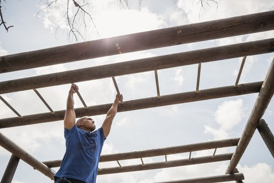 Fit man climbing horizontal bars during obstacle course
