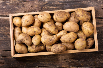 fresh potatoes in wooden box on wooden table