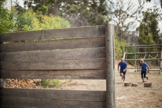 Fit man and woman running during obstacle course