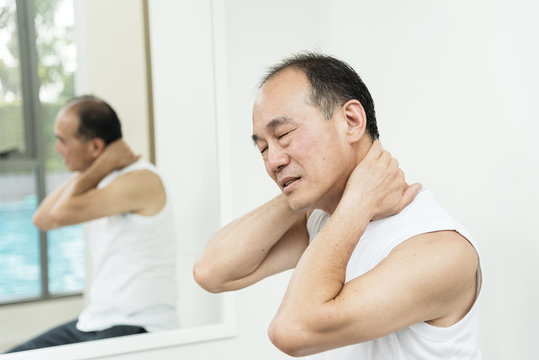 Asian senior man having pain on his shoulder and neck. copy space.