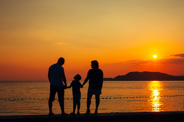 Silhouette of parents with a child at sea. Family on the beach in Montenegro.