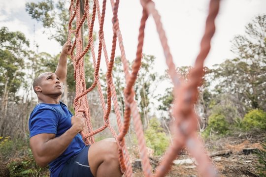 Fit man climbing a net during obstacle course
