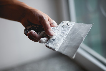 Spatula in hand, plaster, building materials