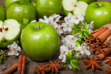 Green apples, cinnamon on a wooden background