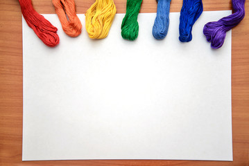 Multicolored embroidery floss on a white sheet