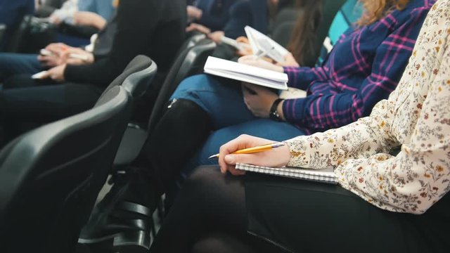 Listeners participating in a lecture - people writing into their notebooks