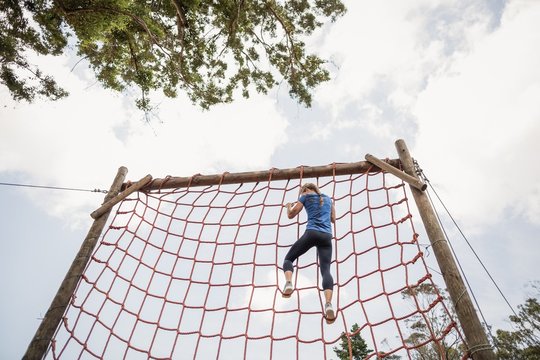 Fit woman climbing down the net during obstacle course