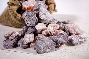 Closeup of dried candied fruits and vegetables in the sack on wooden surface