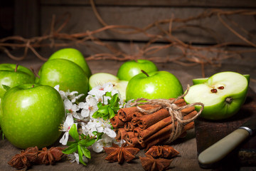 Green apples, cinnamon on a wooden background